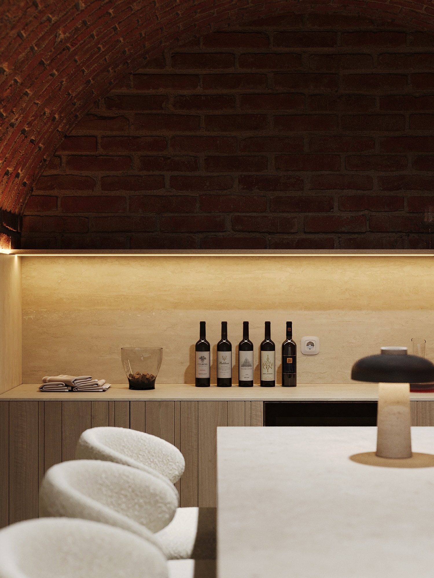Wine bottles on an oak counter beneath brick vaults